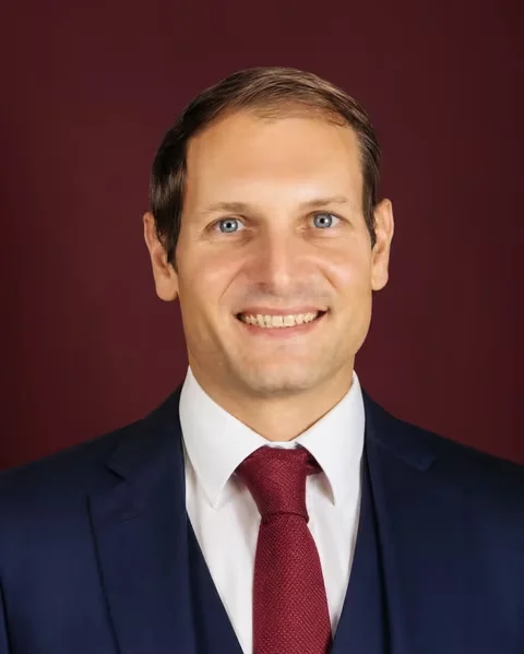 Portrait de Benjamin Duplaa, formateur et fondateur de l'IFPA Poitiers, en costume marine sur fond bordeaux.